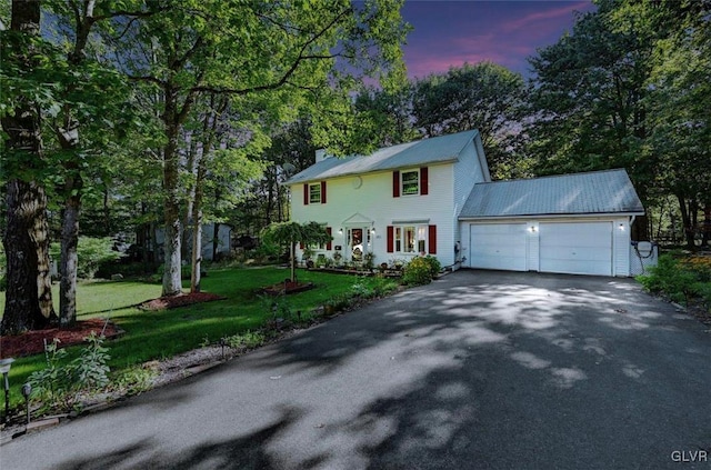 colonial home featuring a garage and a yard