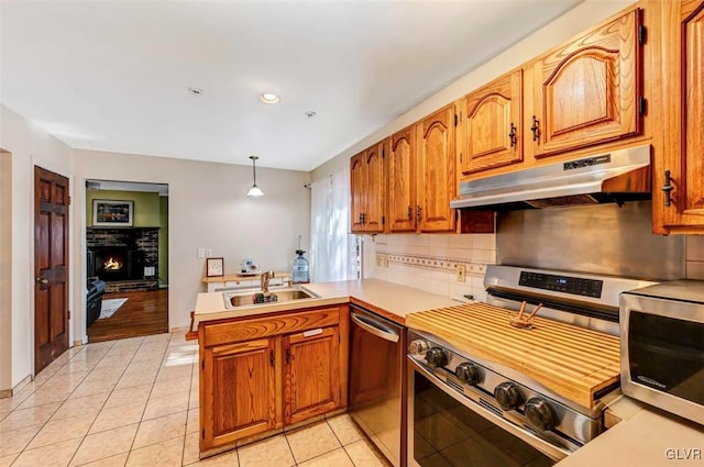 kitchen featuring sink, hanging light fixtures, kitchen peninsula, light tile patterned floors, and appliances with stainless steel finishes