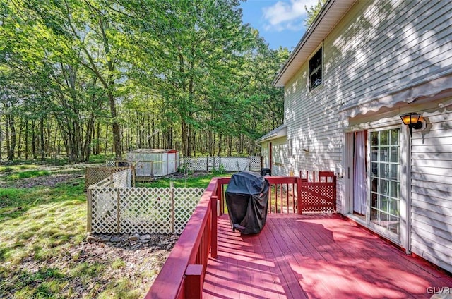 wooden terrace with a lawn, a grill, and a storage shed