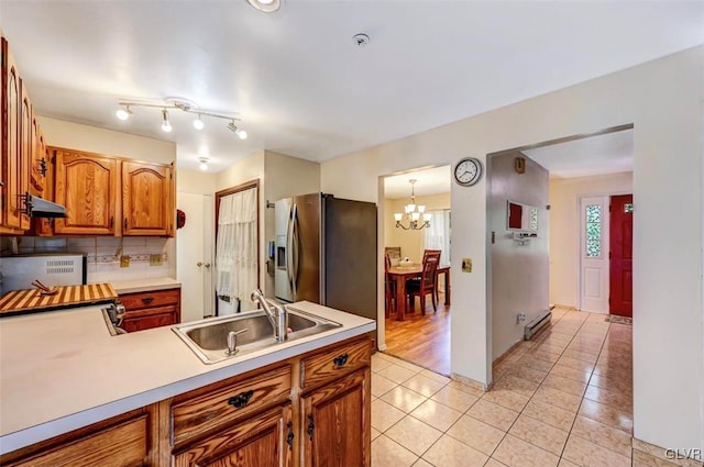 kitchen with backsplash, sink, a chandelier, stainless steel fridge with ice dispenser, and hanging light fixtures