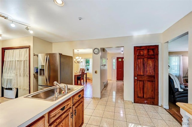 kitchen featuring pendant lighting, sink, stainless steel refrigerator with ice dispenser, light tile patterned flooring, and a chandelier