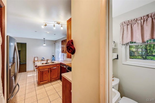 kitchen with sink, stainless steel appliances, kitchen peninsula, pendant lighting, and light tile patterned floors