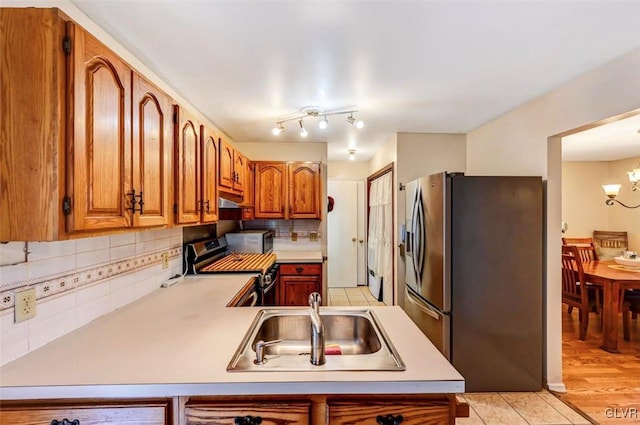 kitchen featuring sink, stainless steel appliances, backsplash, kitchen peninsula, and light hardwood / wood-style floors