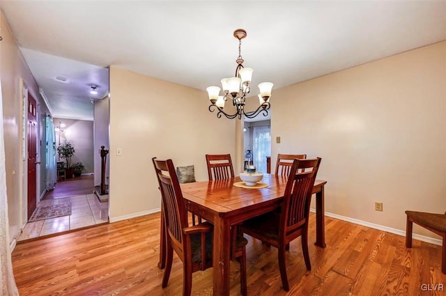 dining room with light hardwood / wood-style floors and an inviting chandelier