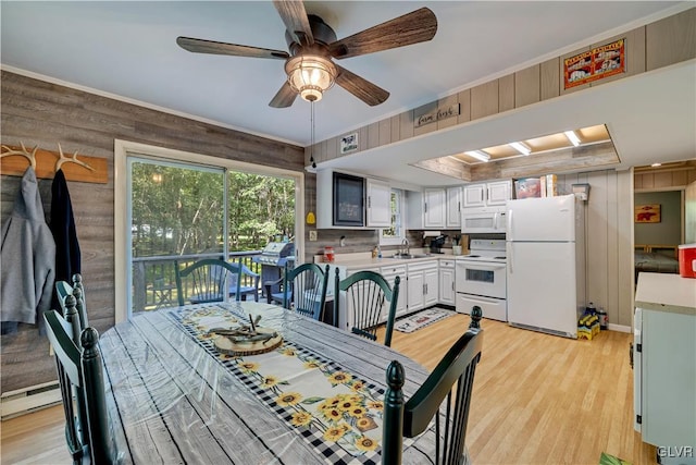 dining room featuring wood walls, sink, ceiling fan, and light hardwood / wood-style floors