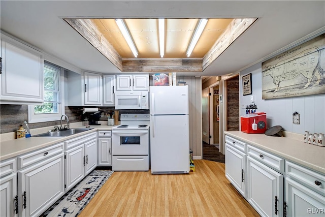 kitchen with white cabinetry, a tray ceiling, white appliances, sink, and light wood-type flooring