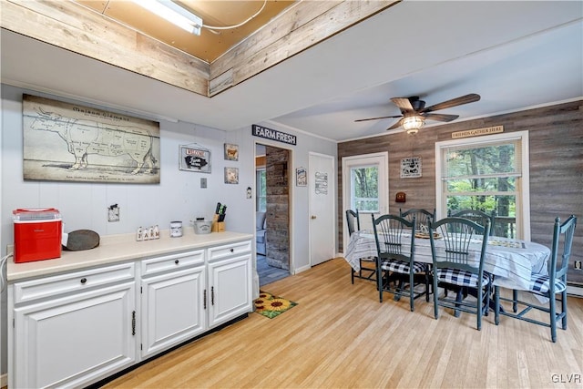 kitchen with ceiling fan, light hardwood / wood-style flooring, wood walls, and white cabinetry