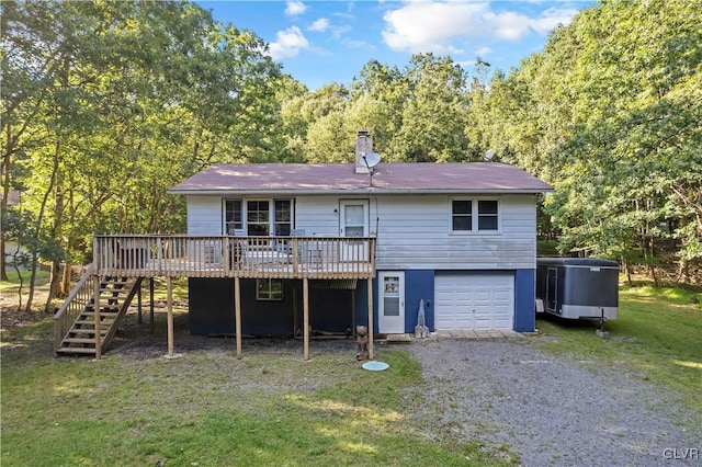 rear view of property with a yard, a garage, and a wooden deck