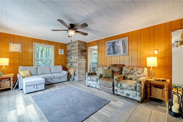 living room with ceiling fan, light hardwood / wood-style flooring, and wooden walls