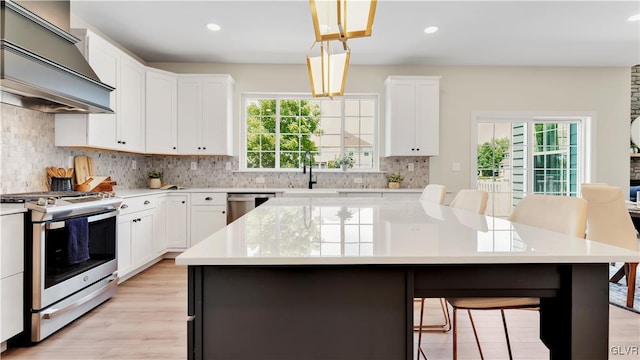 kitchen with backsplash, gas stove, custom exhaust hood, and light hardwood / wood-style floors