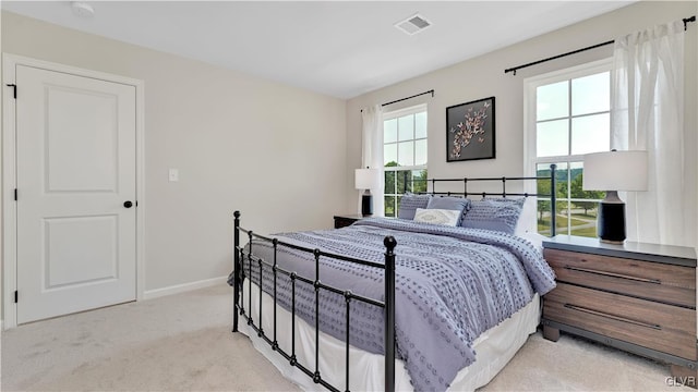 bedroom featuring light colored carpet and multiple windows