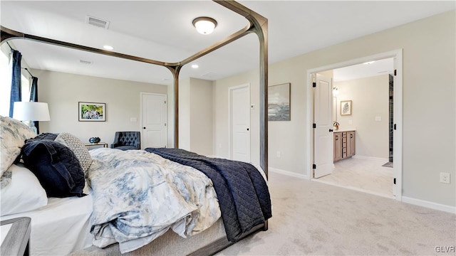 bedroom with light colored carpet and ensuite bathroom