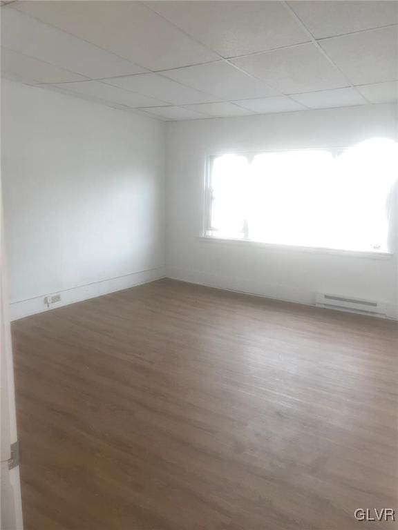 spare room featuring hardwood / wood-style floors, a paneled ceiling, and a healthy amount of sunlight