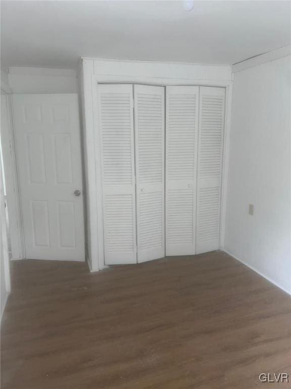 unfurnished bedroom with dark hardwood / wood-style flooring and a closet