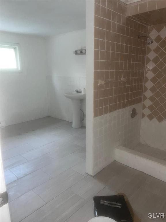 bathroom featuring sink, tile patterned flooring, a tile shower, and tile walls