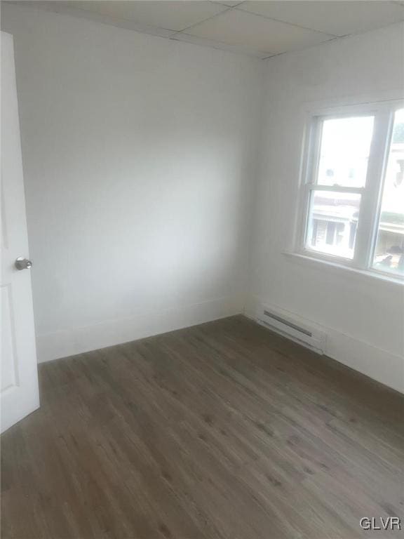 empty room with baseboard heating and dark wood-type flooring