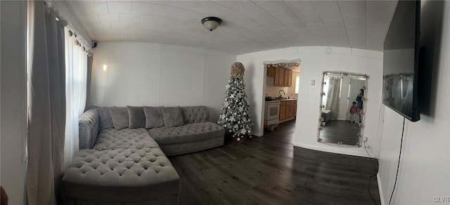 living room featuring sink, dark hardwood / wood-style floors, vaulted ceiling, and brick ceiling