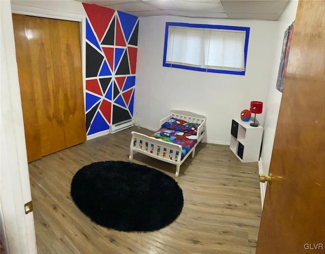 bedroom with hardwood / wood-style floors, a paneled ceiling, and a closet