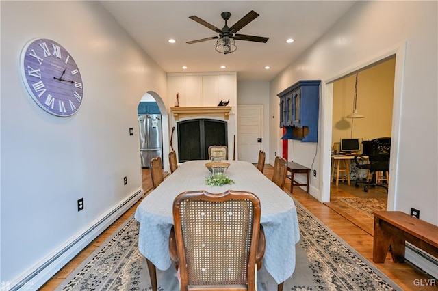 dining room with hardwood / wood-style floors, baseboard heating, and ceiling fan