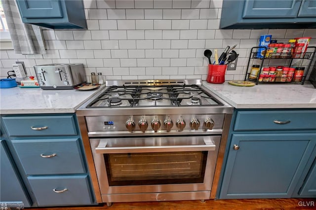 kitchen with blue cabinets, decorative backsplash, and stainless steel range