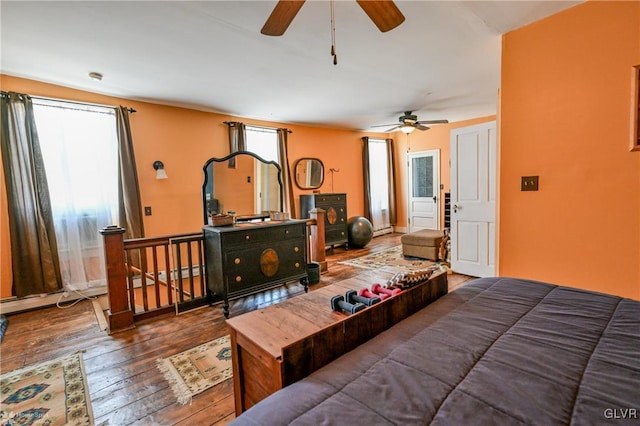 bedroom featuring a baseboard heating unit, ceiling fan, and dark hardwood / wood-style floors