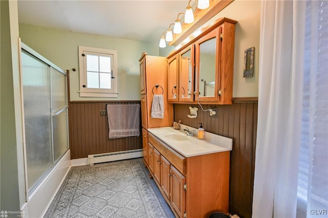 bathroom with baseboard heating, vanity, and bath / shower combo with glass door