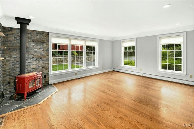 unfurnished living room featuring dark hardwood / wood-style floors, brick wall, a wood stove, a baseboard heating unit, and crown molding