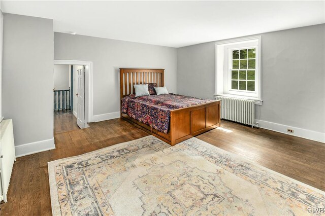 bedroom with radiator heating unit and dark wood-type flooring