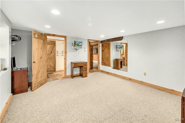 unfurnished living room with a barn door and light carpet