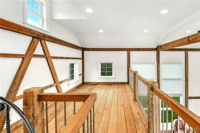 hall with a wealth of natural light, vaulted ceiling, and light hardwood / wood-style flooring