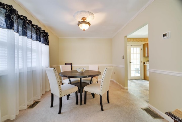 dining area featuring ornamental molding and light colored carpet