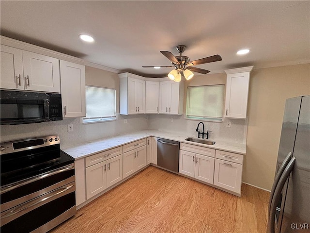 kitchen featuring appliances with stainless steel finishes, ceiling fan, sink, and light wood-type flooring