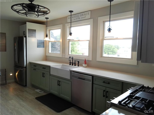 kitchen featuring a sink, hanging light fixtures, light countertops, freestanding refrigerator, and dishwasher