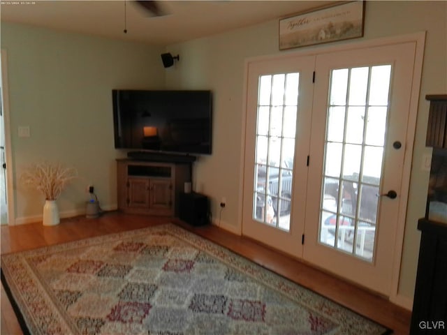 living area with a ceiling fan, baseboards, and wood finished floors