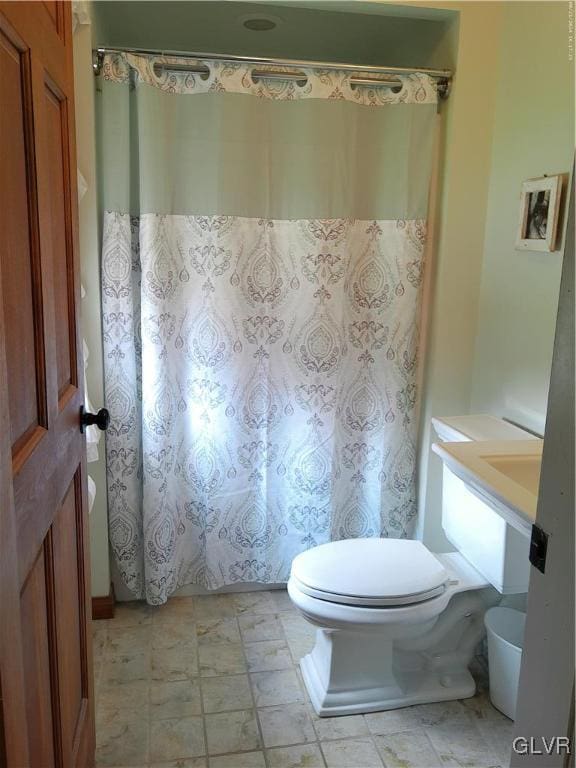 bathroom featuring toilet and curtained shower