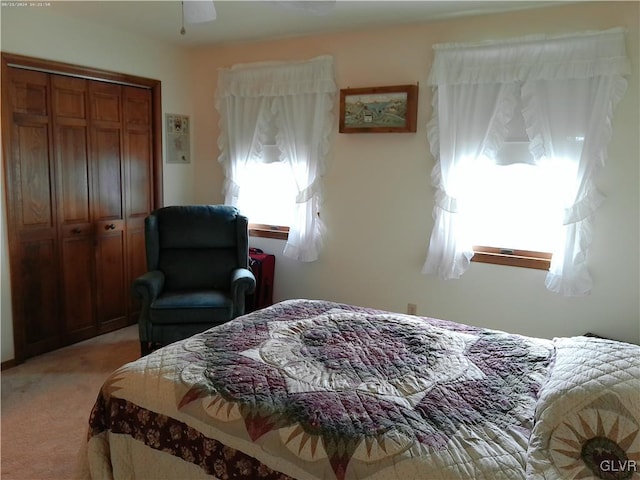 bedroom featuring light carpet, a ceiling fan, and a closet