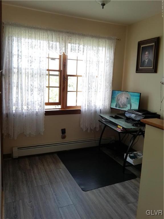 office space featuring plenty of natural light, a baseboard heating unit, and wood finished floors