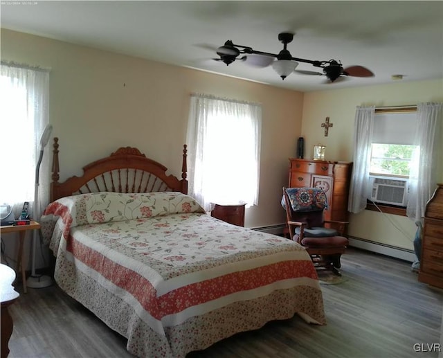 bedroom with cooling unit, a baseboard heating unit, ceiling fan, and wood finished floors