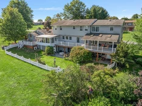 rear view of house with a yard, a deck, and fence