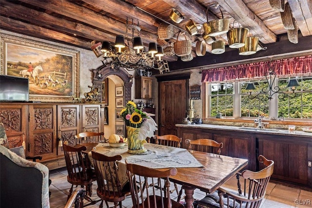 tiled dining room with wooden ceiling, a notable chandelier, beam ceiling, and sink