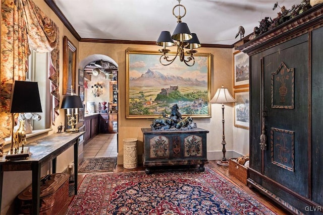 entrance foyer with ornamental molding, wood-type flooring, and an inviting chandelier