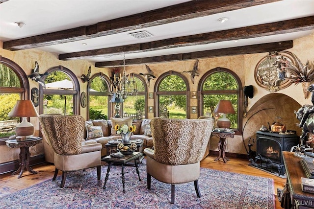 sunroom / solarium featuring a wood stove, an inviting chandelier, and beamed ceiling