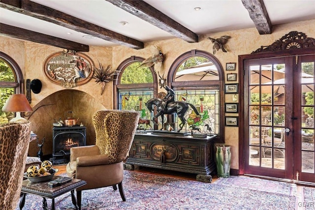 sitting room featuring a wood stove, wood-type flooring, beam ceiling, and french doors