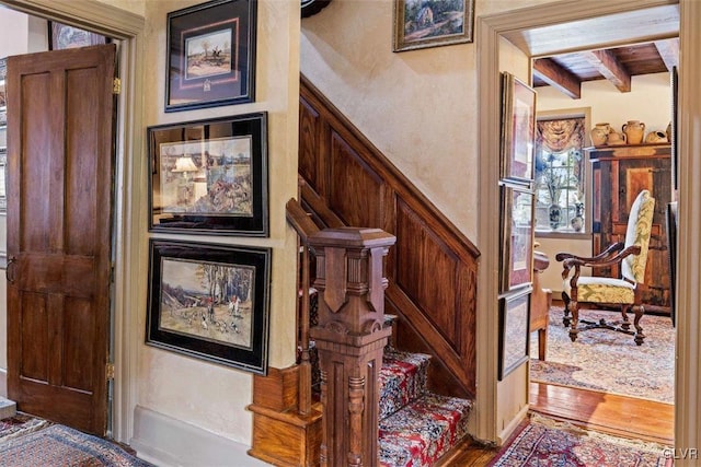 staircase with beamed ceiling and hardwood / wood-style floors