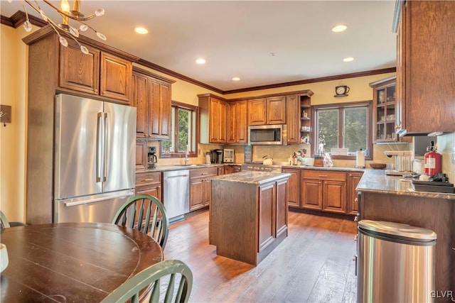 kitchen with appliances with stainless steel finishes, a center island, hardwood / wood-style flooring, and a wealth of natural light