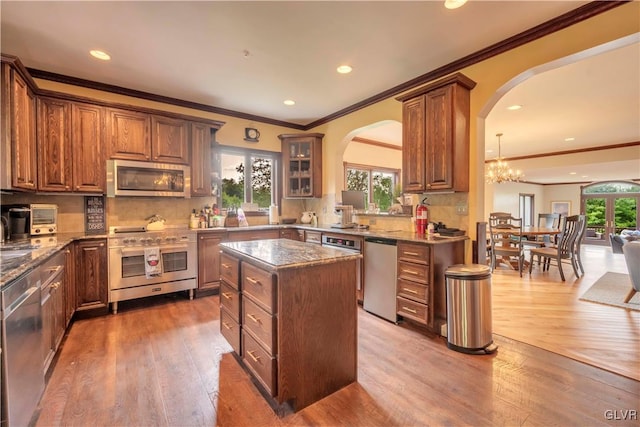 kitchen with hardwood / wood-style floors, appliances with stainless steel finishes, decorative backsplash, and a wealth of natural light