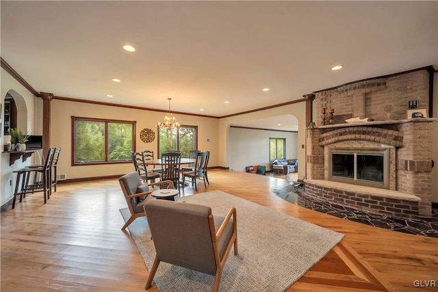 living room featuring a fireplace, crown molding, and light wood-type flooring