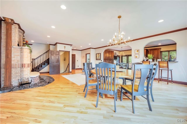 dining area with light hardwood / wood-style flooring, ornamental molding, brick wall, and a chandelier