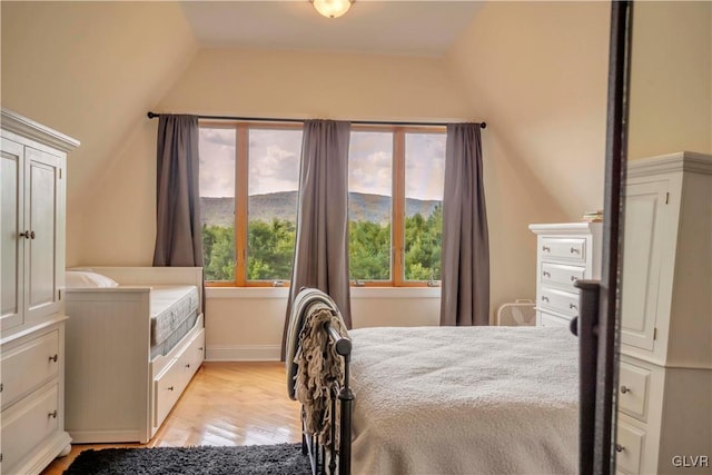 bedroom featuring light hardwood / wood-style floors, a mountain view, and lofted ceiling