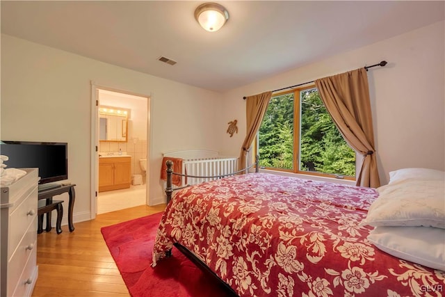 bedroom with ensuite bathroom and light hardwood / wood-style floors